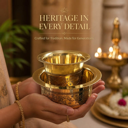 Hands holding brass davara tumbler near oil lamps showcasing heritage elephant motif engraving