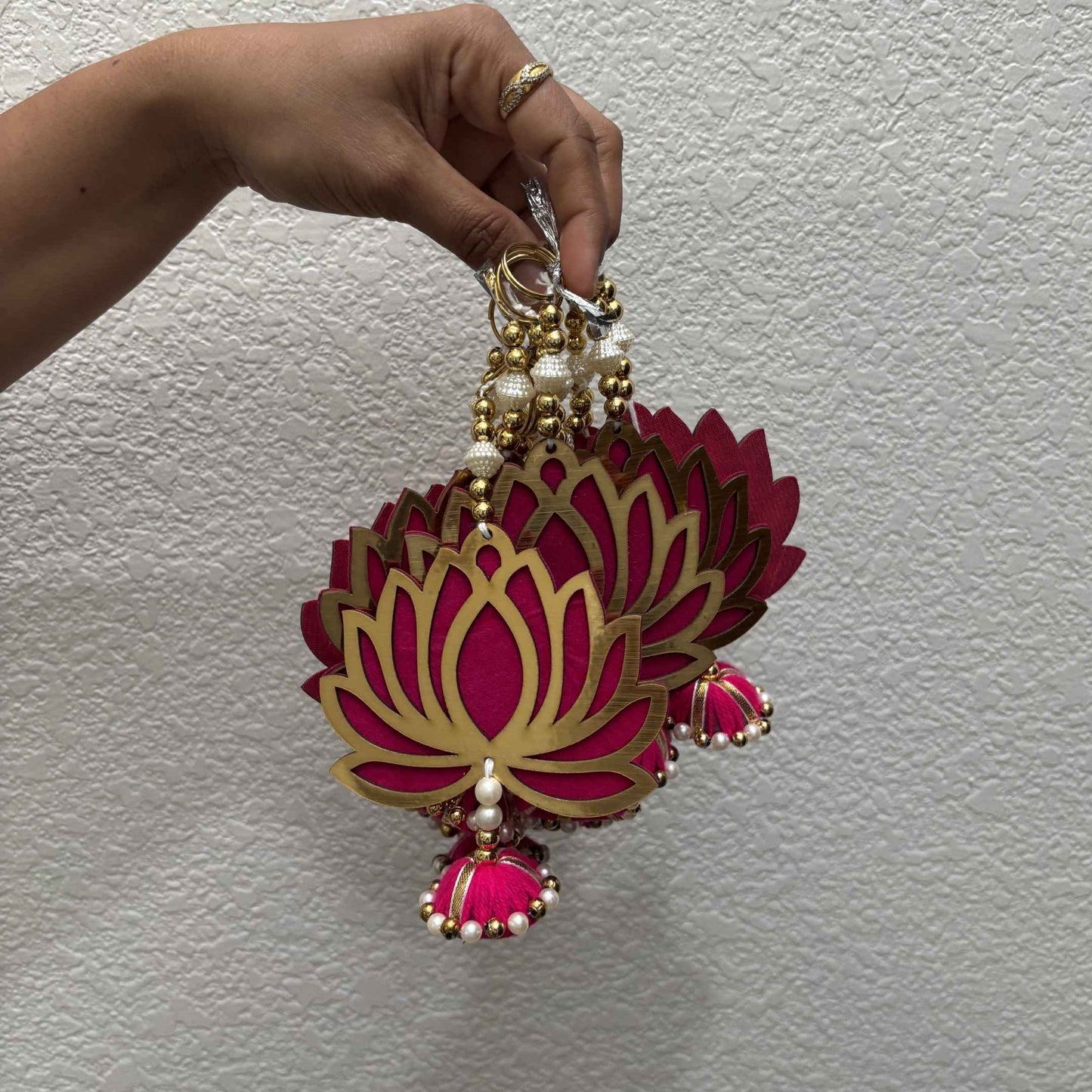 Hand displaying set of short lotus MDF danglers with gold rings, pearl beads and pink fabric jhumkas