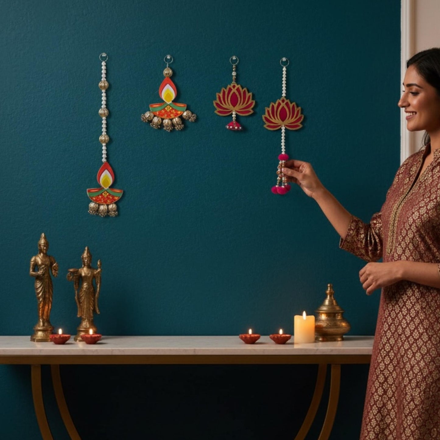 Hand holding short lotus and long diya dangler strings beside teal velvet curtain — Diwali wall decor