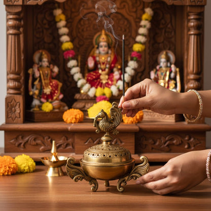 Incense stick burning beside a brass dhoop dani in front of a wooden mandir with deity idols and marigolds