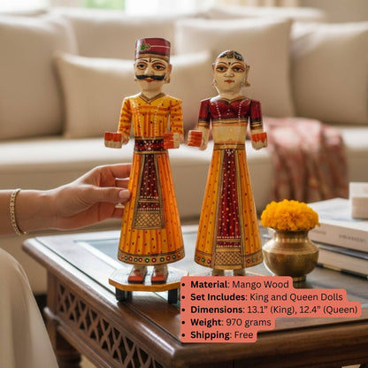 Orange and red hand-painted Isar Gangaur King and Queen dolls held above a coffee table with a spec overlay