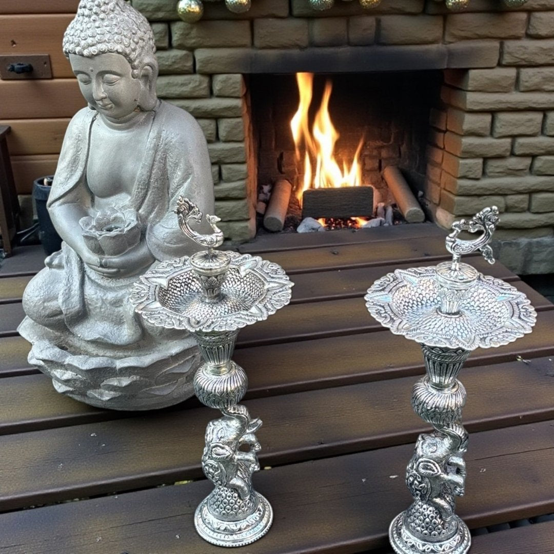 Buddha statue with German silver antique silver samai oil lamps in home decor arrangement – Urli Utsav