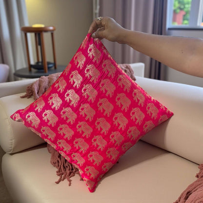 Person holding a pink pillow with elephant patterns on a beige sofa.