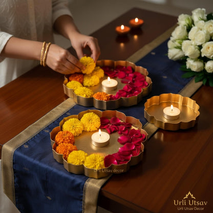 Decorative arrangement with flowers and candles on a table, featuring 'Urli Utsav Decor' ethcing plate set.
