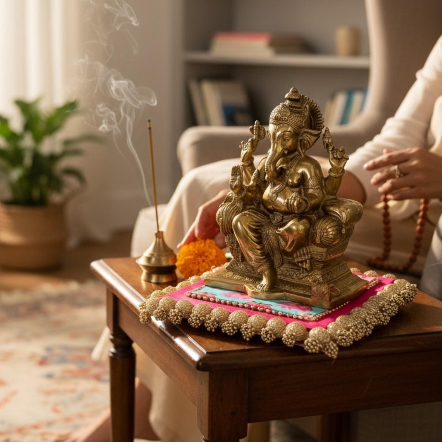 Bronze-toned Ganesha statue with incense and flowers in home altar setting — devotional decor