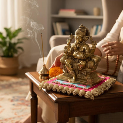 Bronze-toned Ganesha statue with incense and flowers in home altar setting — devotional decor