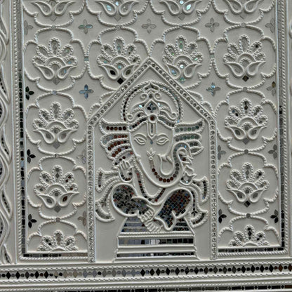 Decorative panel with intricate patterns and a central figure, likely a deity, on a white background.