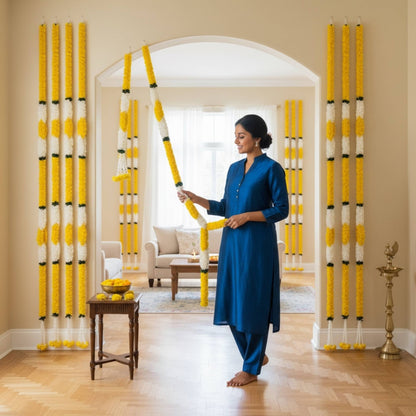 Woman hanging yellow white marigold jasmine fabric garlands on arched doorway – Indian festive home decor for Diwali and housewarming