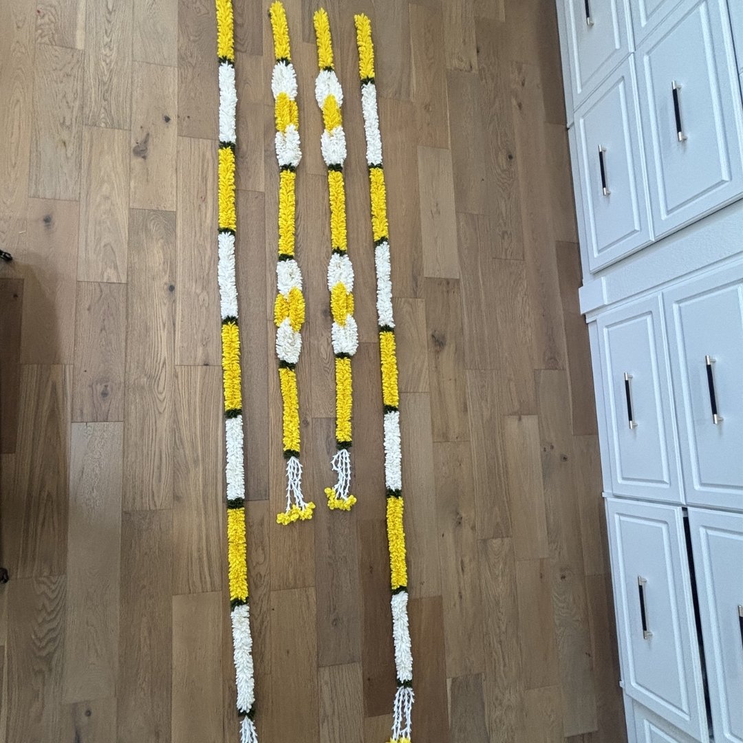 Yellow jasmine marigold fabric garlands flat lay on floor showing full string length