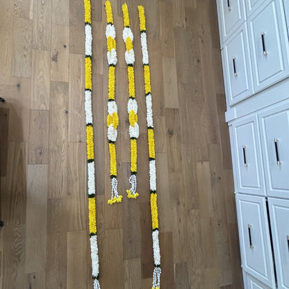Yellow jasmine marigold fabric garlands flat lay on floor showing full string length