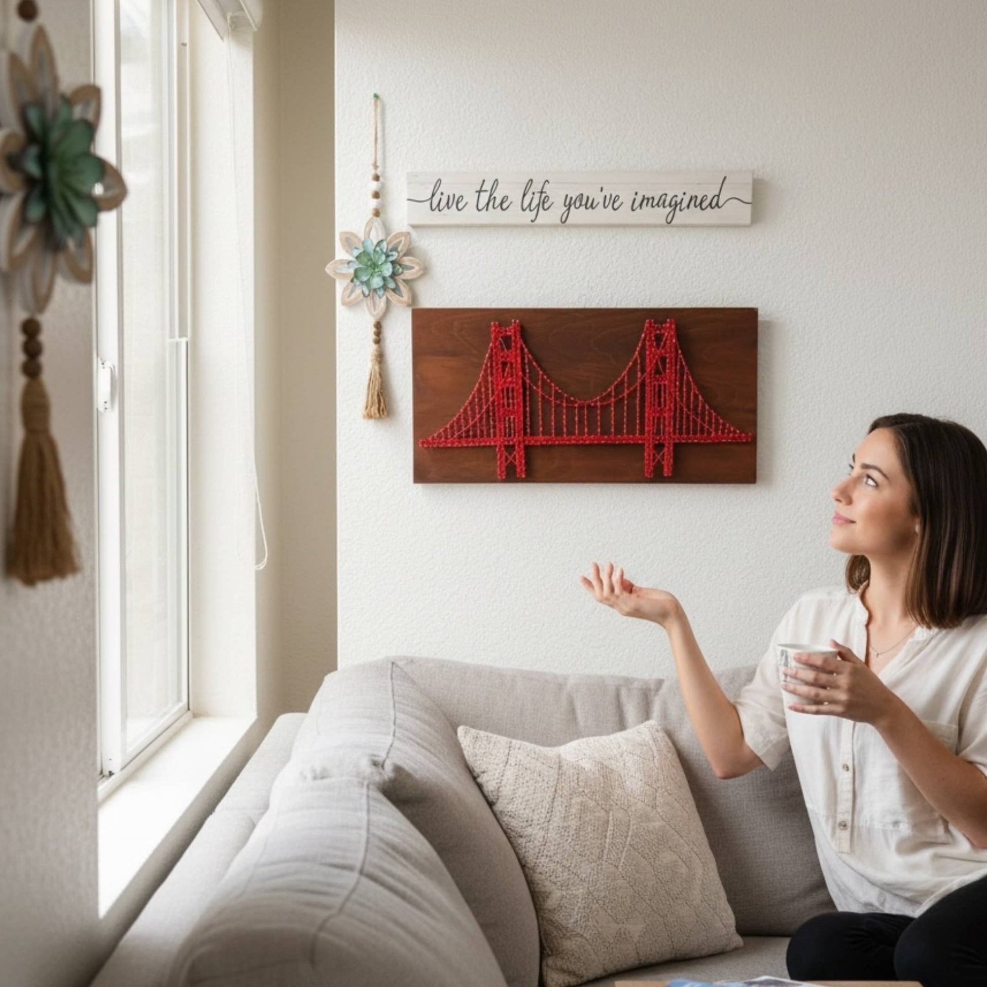 Woman sitting on a couch holding a mug, with decorative wall art and a motivational quote in the background.