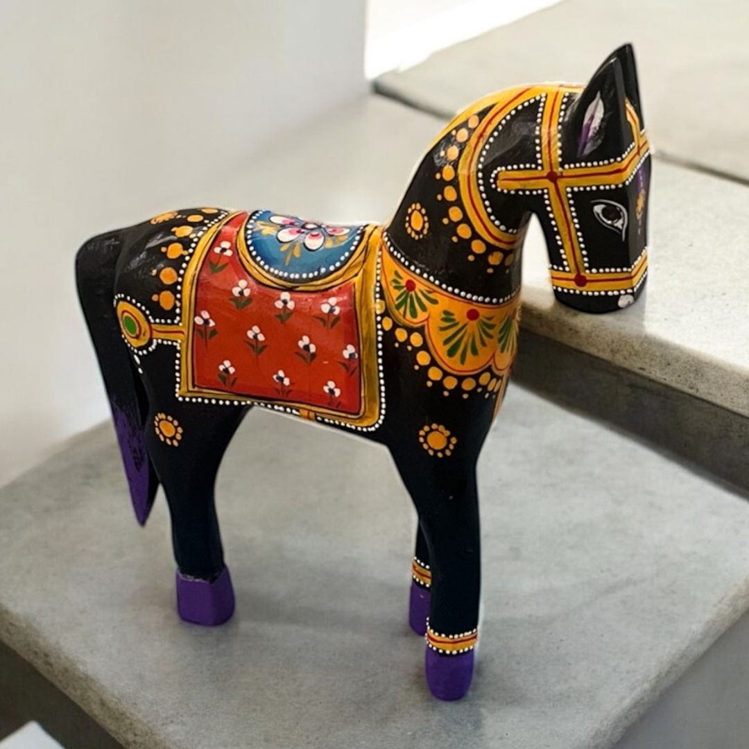 Decorative horse figurine with black patterns on a gray surface