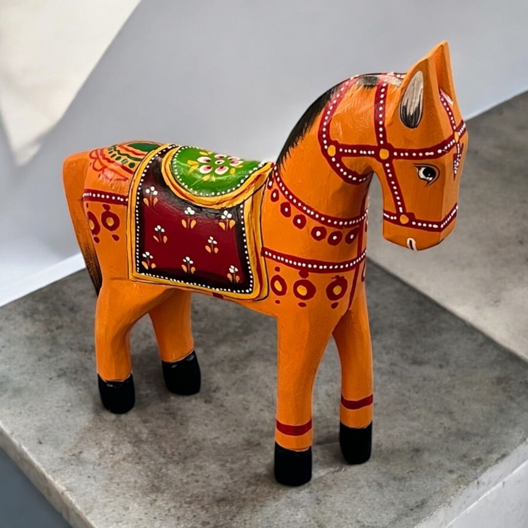 Decorative horse figurine with orange patterns on a gray surface