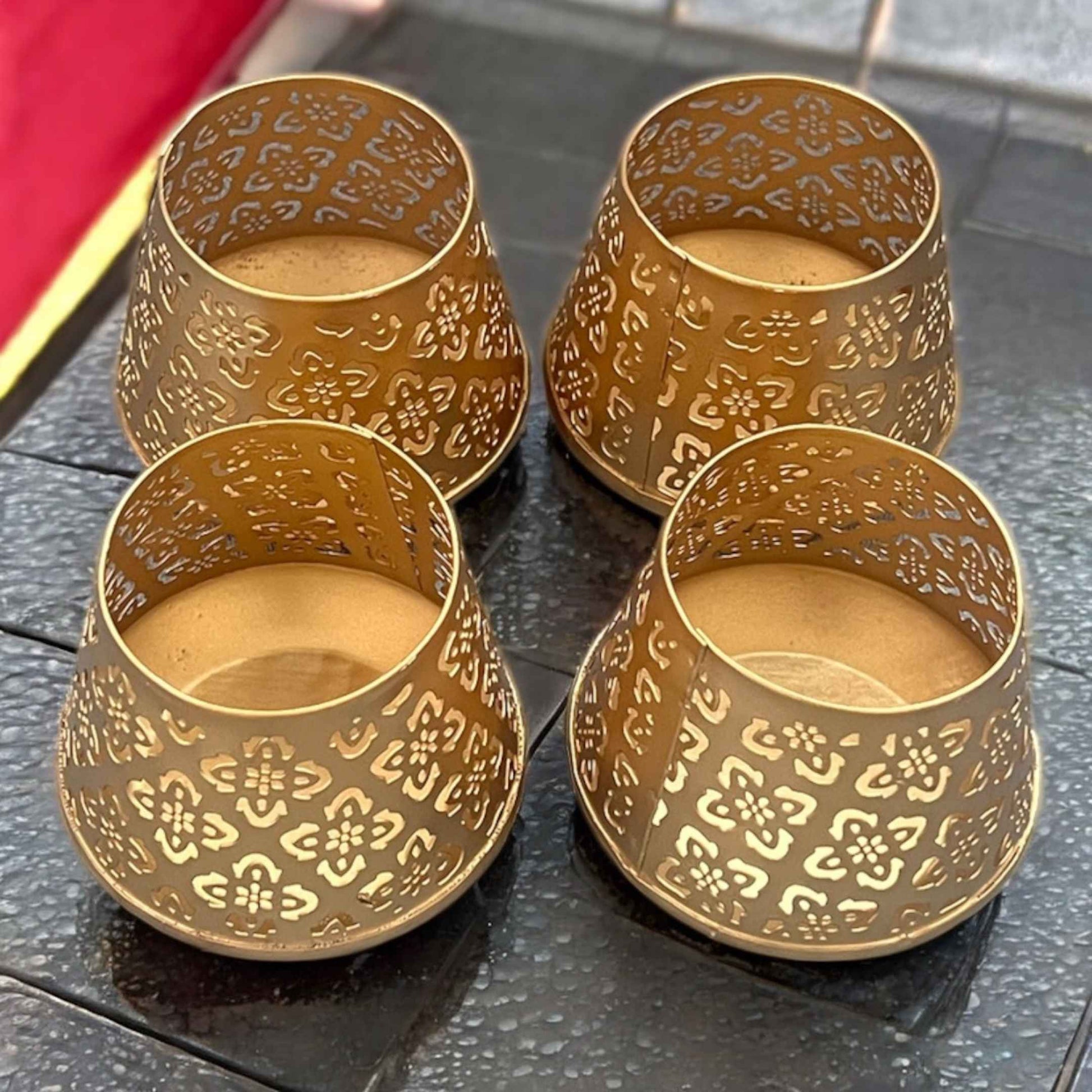 Four gold ornate t-lights on a dark surface