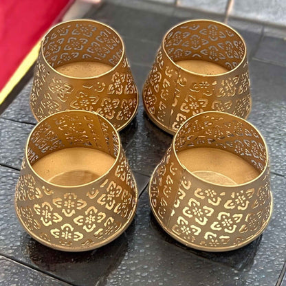 Four gold ornate t-lights on a dark surface