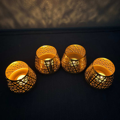 Four ornate gold candle holders with intricate designs on a dark background.