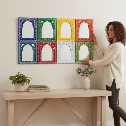 Woman arranging colorful jharokha wall art on a white wall