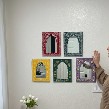 Five decorative jharokha mirrors of different colors and designs on a wall