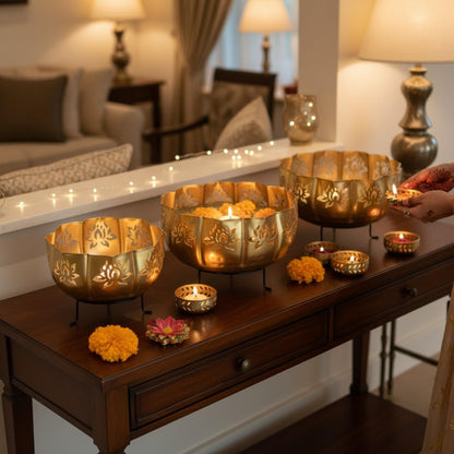 Decorative gold urli bowls with candles on a wooden table in a home setting