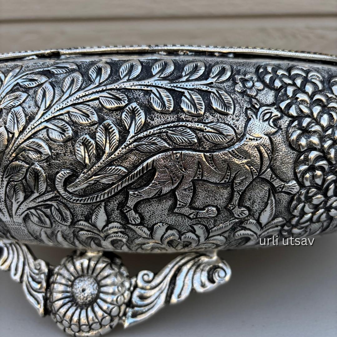 Close up of Jungle theme german silver urli bowl with intricate leaf and animal patterns on a neutral background