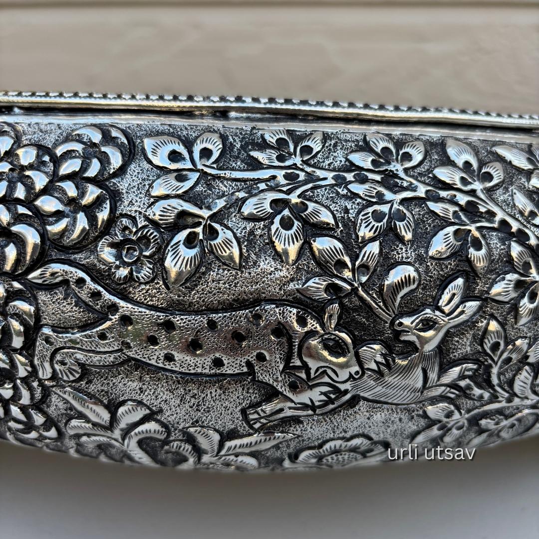 Close up of Jungle theme german silver urli bowl embossed urli with deer and floral design on a beige background
