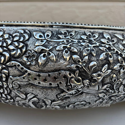 Close up of Jungle theme german silver urli bowl embossed urli with deer and floral design on a beige background