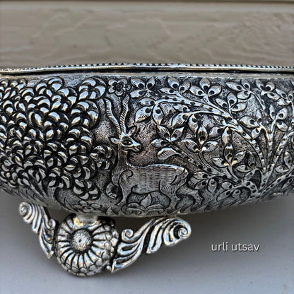 Close up of Jungle theme german silver urli bowl with intricate floral and deer designs on a light background
