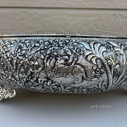 Close up of Jungle theme german silver urli bowl with intricate floral and paisley patterns on a neutral background.