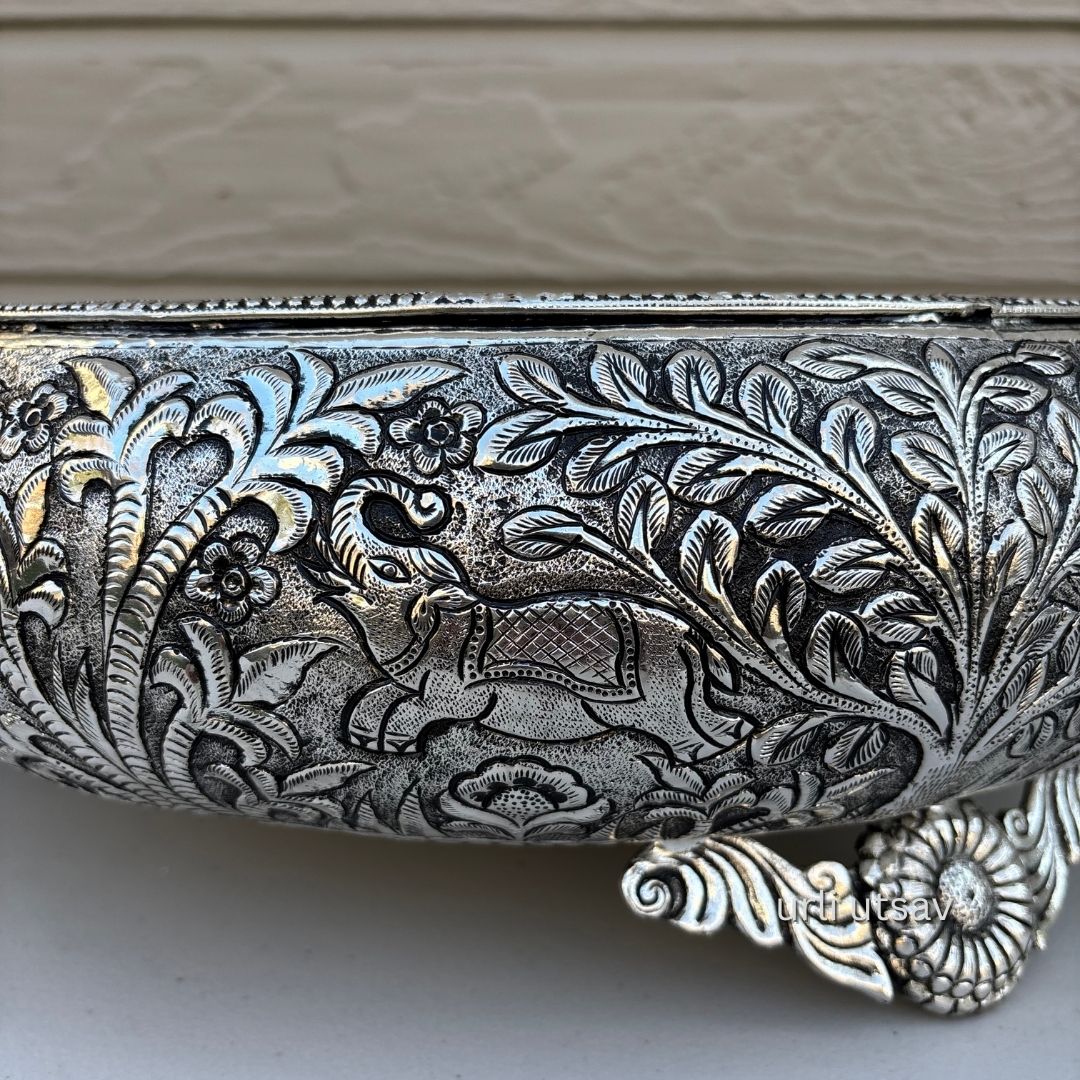 Close up of Jungle theme german silver urli bowl  with intricate floral patterns on a neutral background