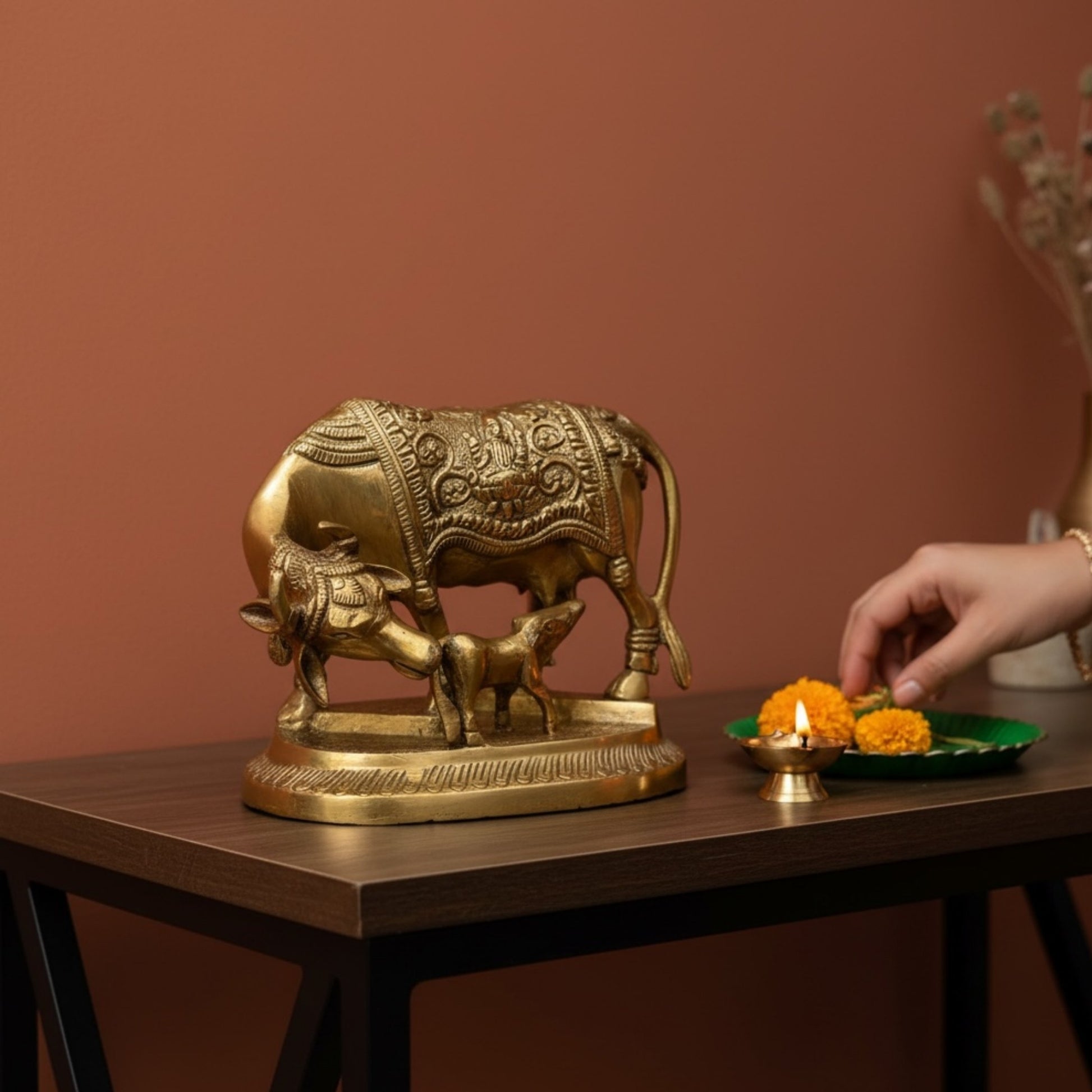 Brass Kamdhenu Cow and Calf idol styled with diya and marigolds for Diwali home decor