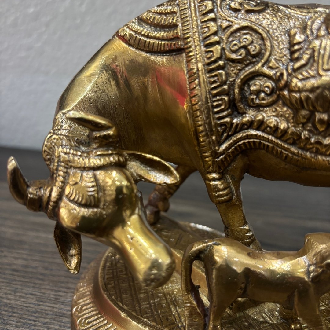 Close-up of handcrafted brass cow and calf idol showing intricate carved engravings