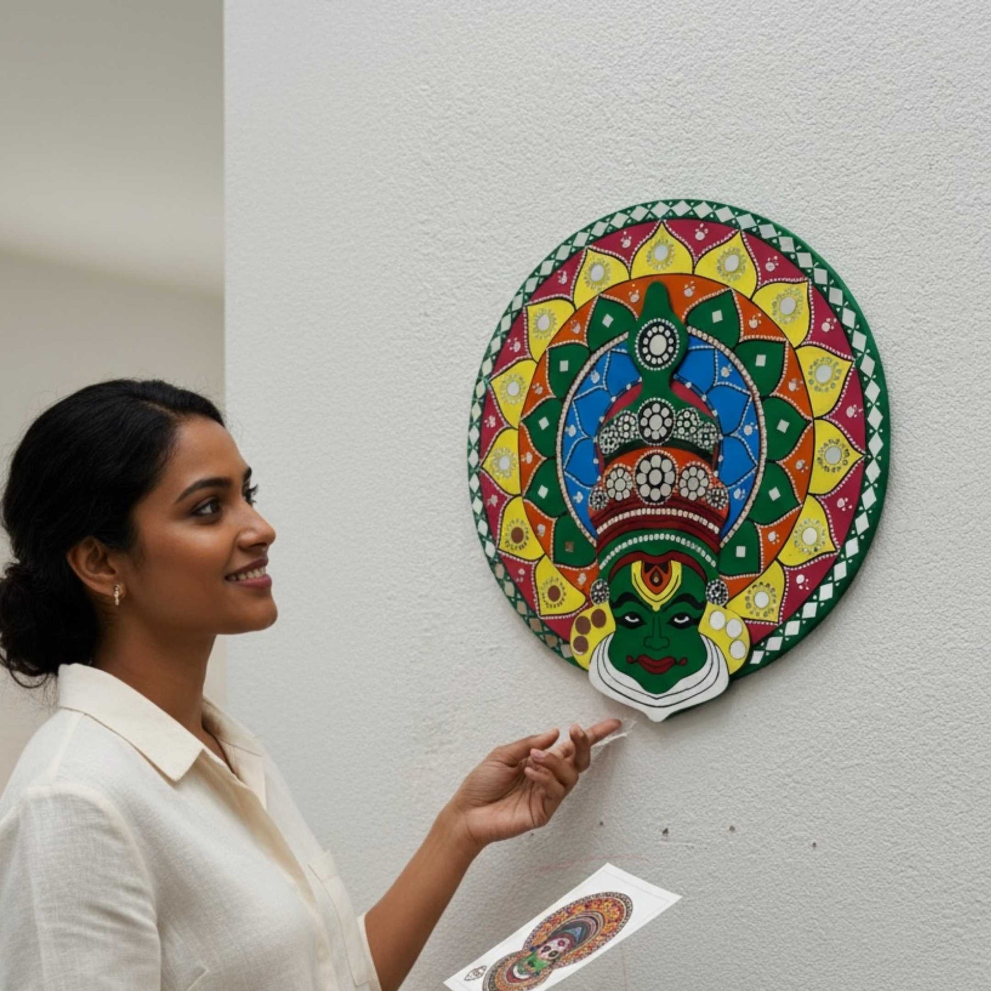 Woman admiring colorful kathakali wall art design on a white wall