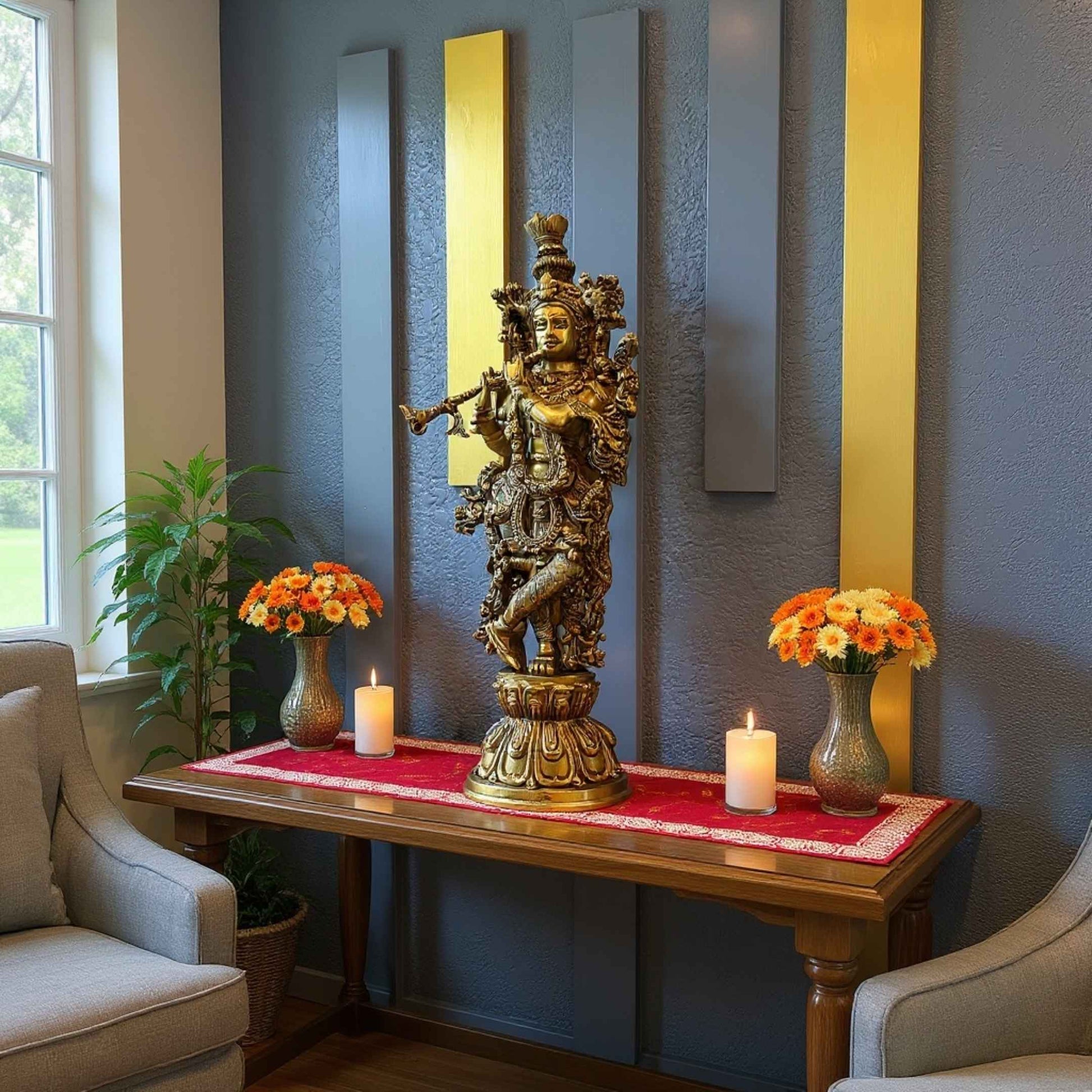 Brass Krishna statue styled on a wooden console table in a living room, with a red runner, candles and flower arrangements against a blue wall with gold and gray panels