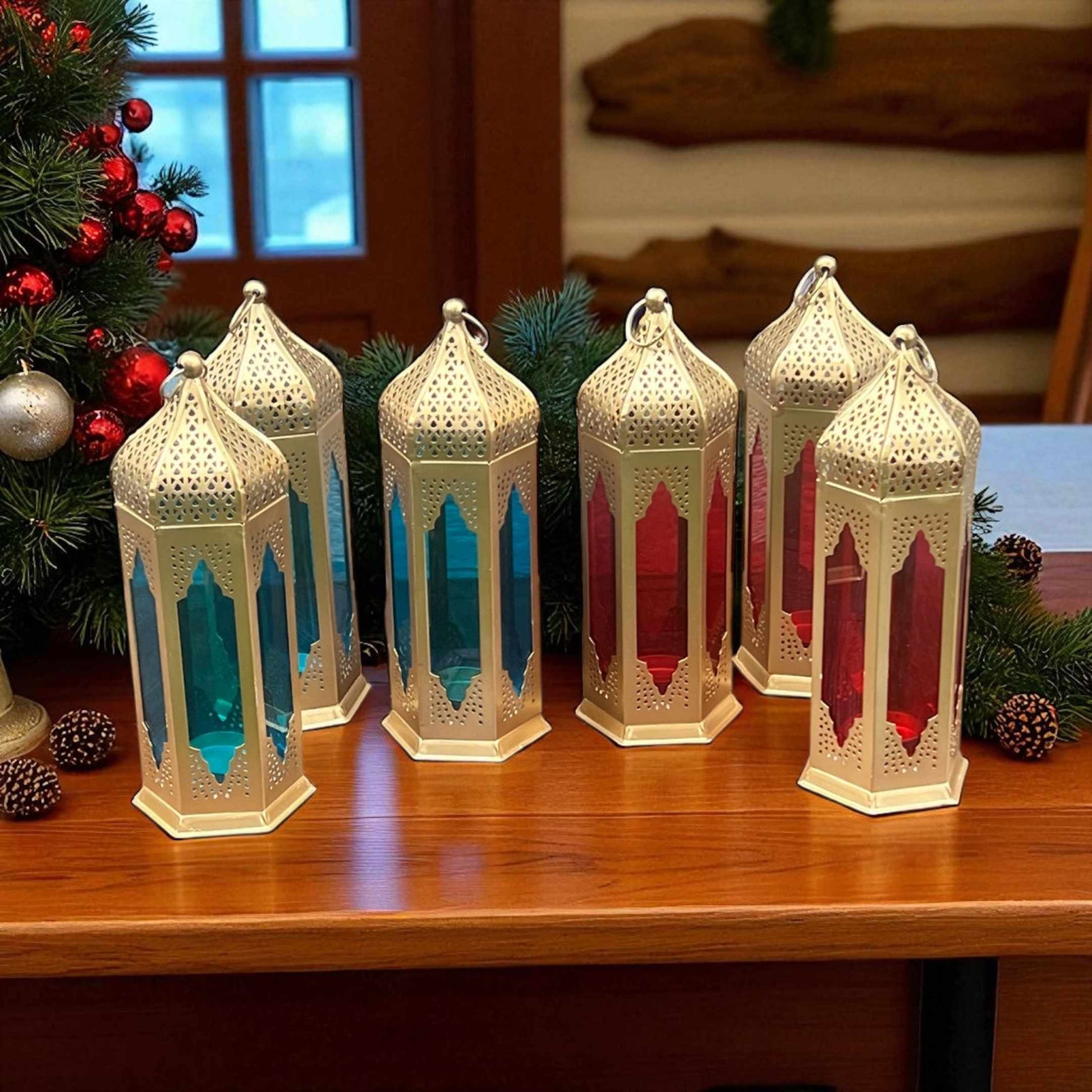 Moroccan-style lanterns with red and blue stained glass panels on a table, complementing festive decorations like a Christmas tree.