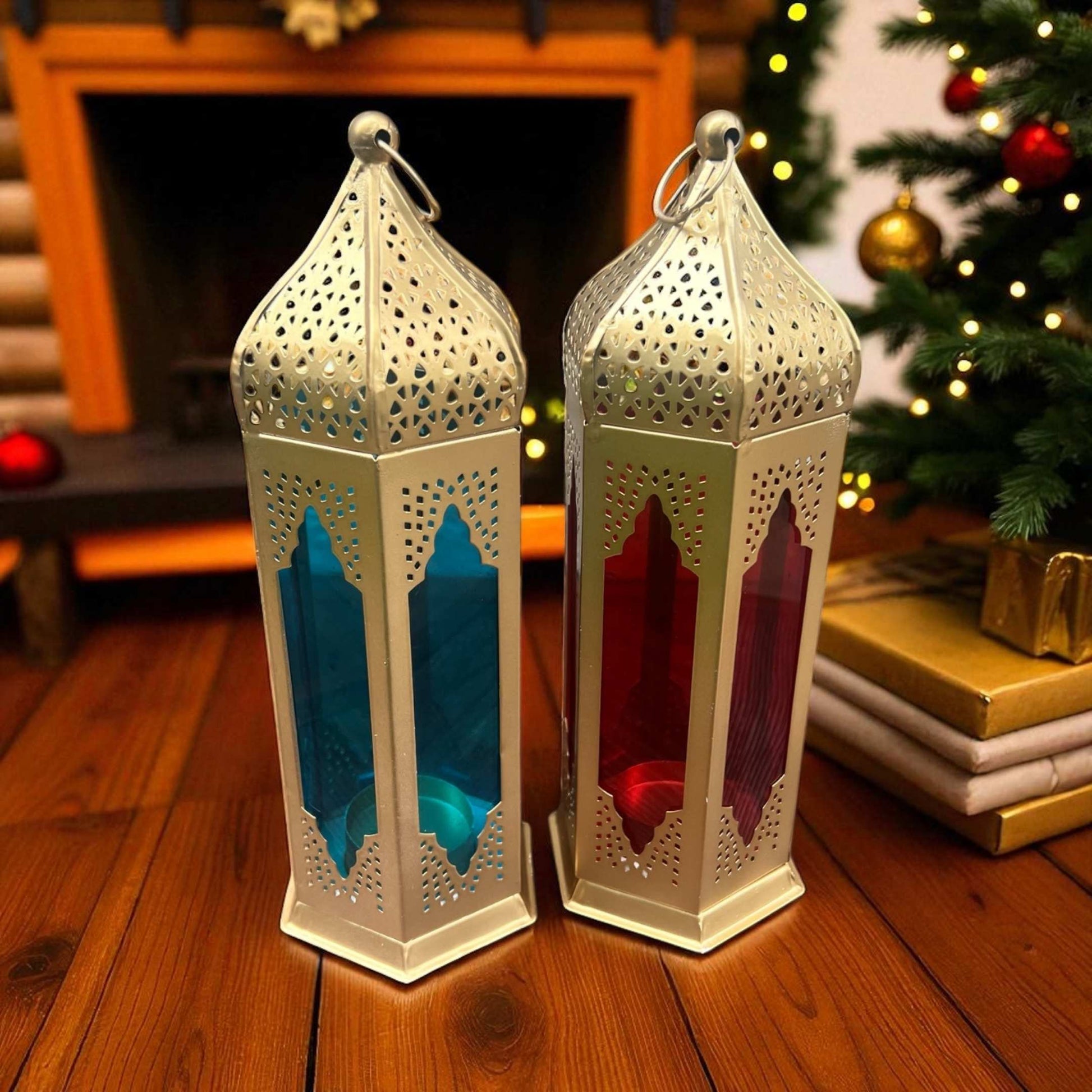 Pair of Moroccan-style lanterns with blue and red stained glass panels, placed on a wooden floor, adding a festive touch near a Christmas tree.