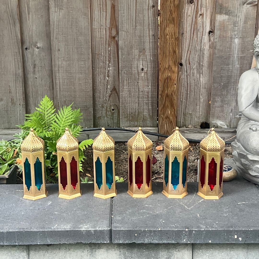 Collection of Moroccan lanterns with red and blue stained glass panels, arranged on a stone surface, adding a festive touch to outdoor décor.