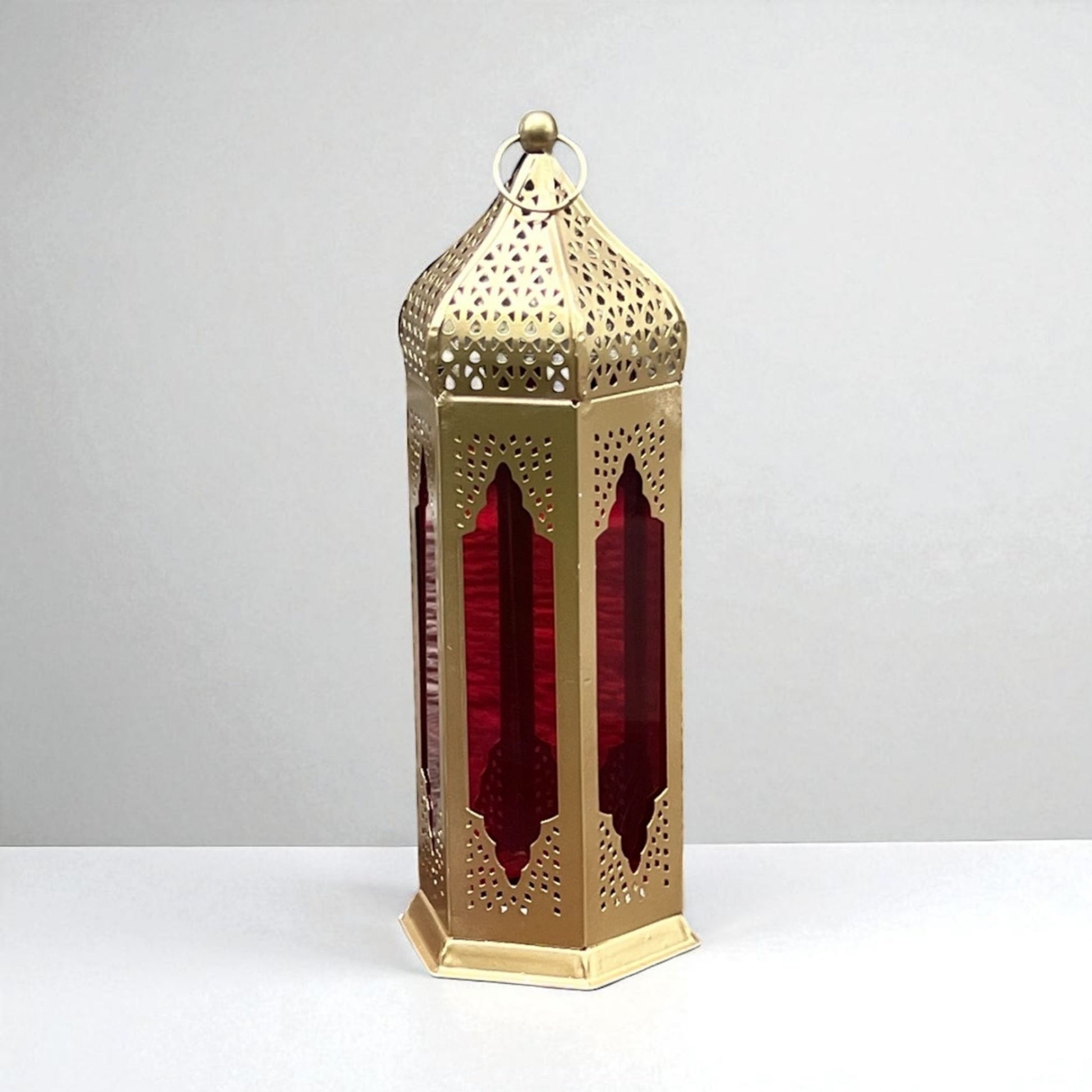Detailed view of a Moroccan-style lantern with red stained glass panels and gold metal filigree, highlighting its handcrafted artistry.