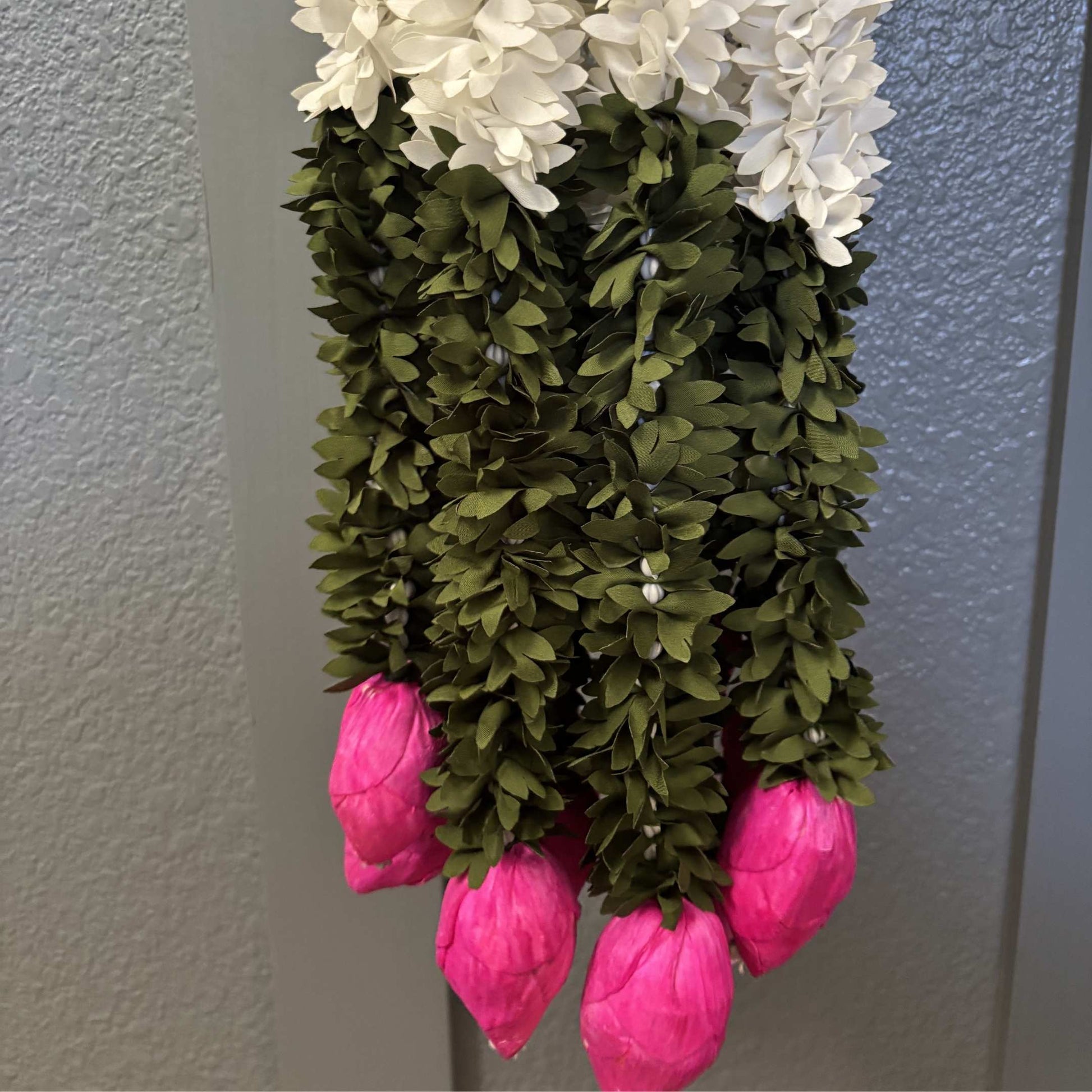 Close-up of 5-foot white jasmine and pink lotus bud fabric garland on stone surface – handmade artificial Indian garland with sola wood buds and faux pearls