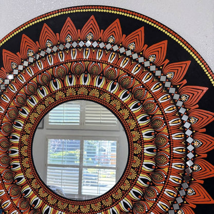 Round mandala mirror with intricate orange patterns hung on plain wall