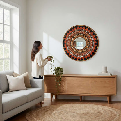 Woman standing beside orange mandala wall mirror in modern living room 