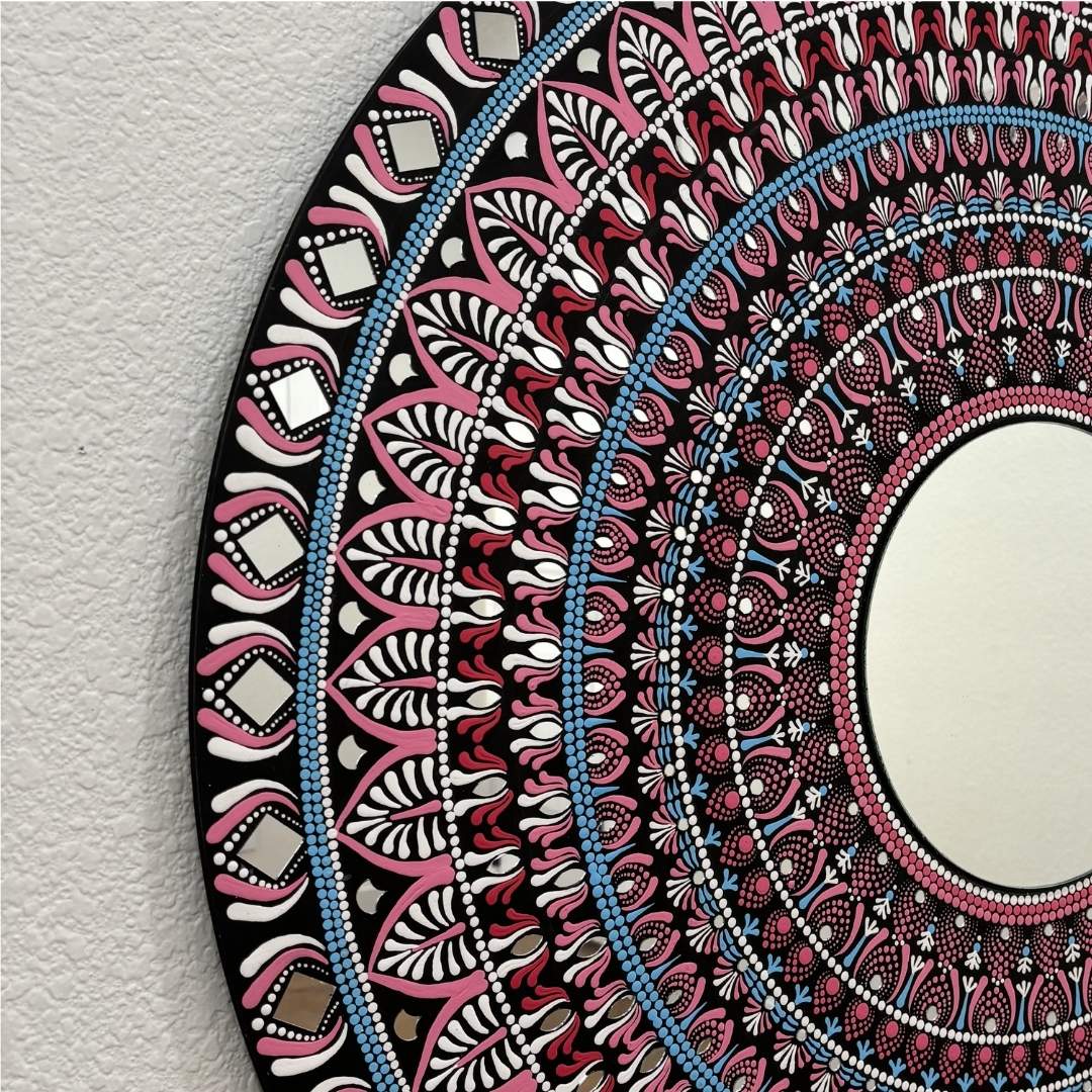 Pink, blue and black mandala mirror pattern close-up on textured white background 