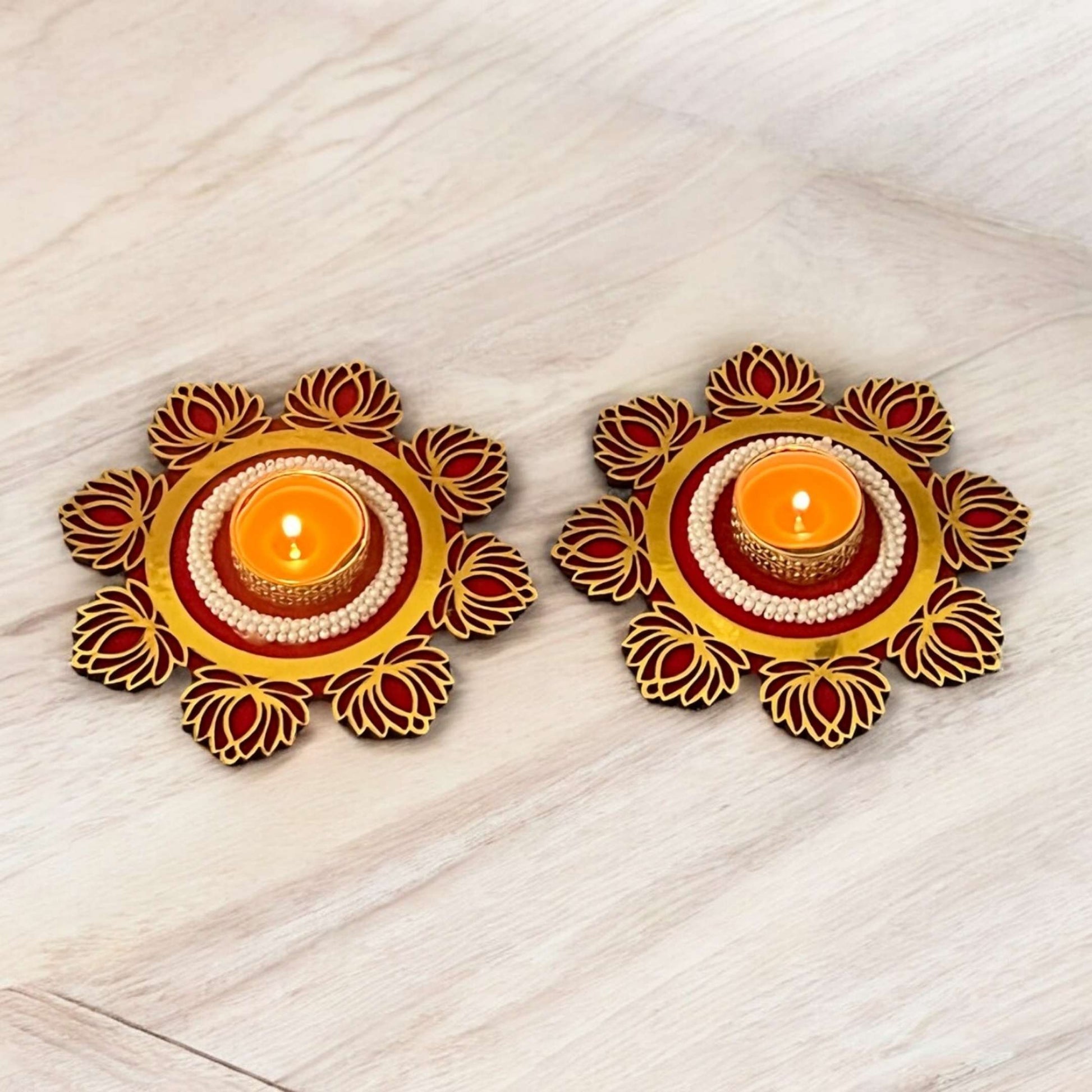 Two decorative candle holders with candles on a light wooden surface
