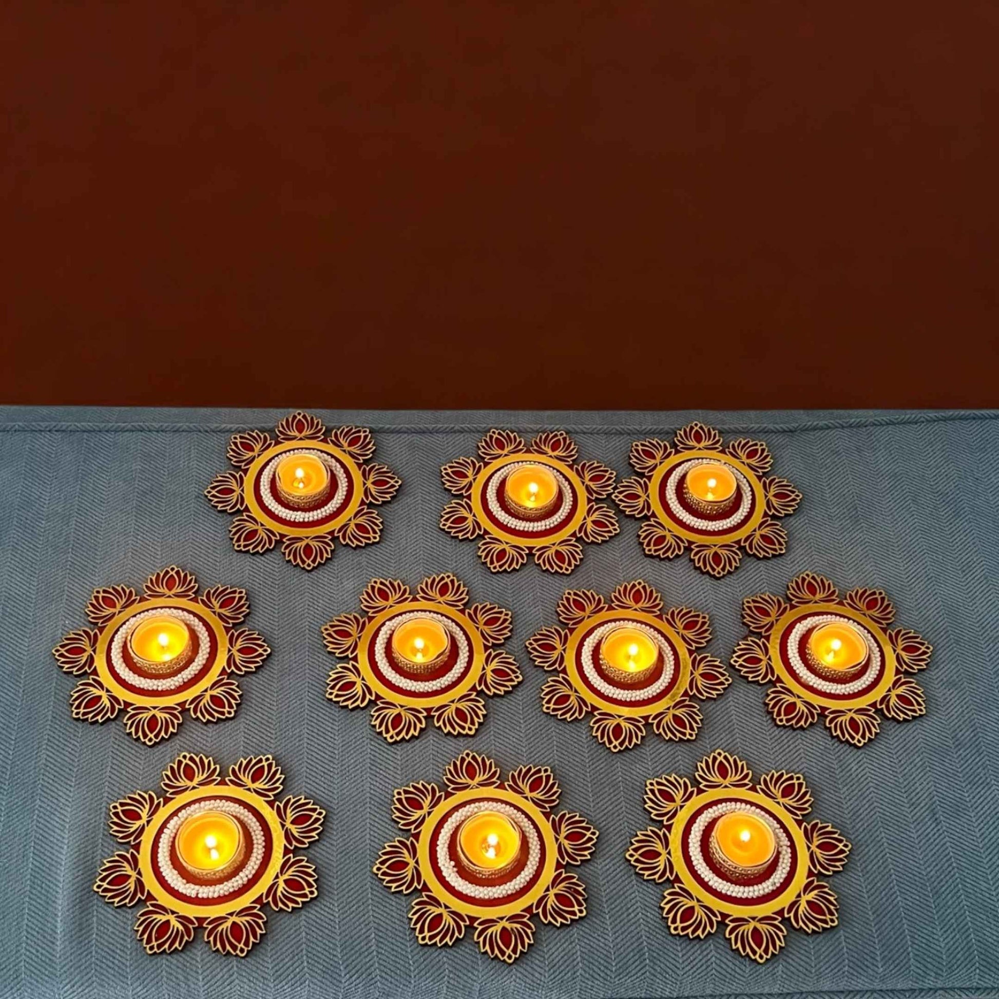 Decorative candles arranged in a circular pattern on a blue surface with a brown background