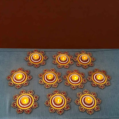 Decorative candles arranged in a circular pattern on a blue surface with a brown background