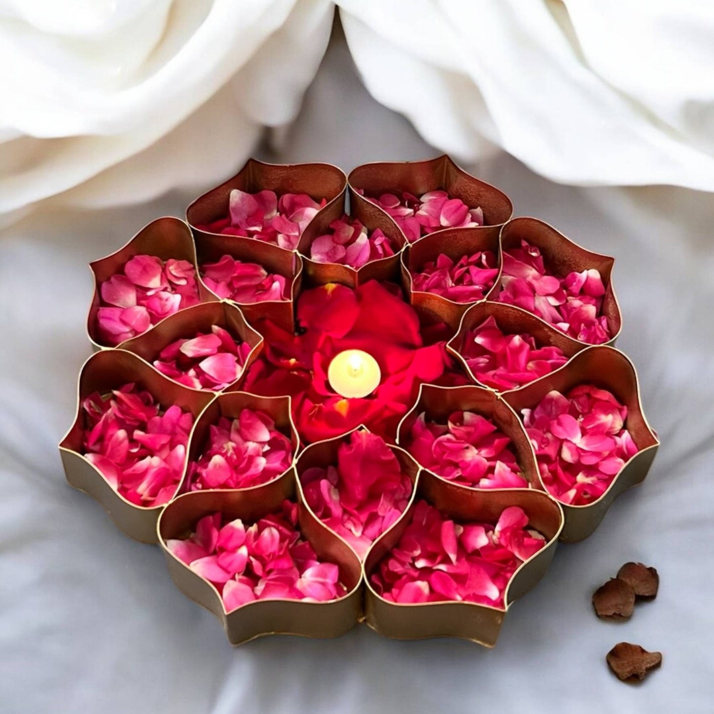 Decorative arrangement with pink petals and a candle in a brown holder on a white background