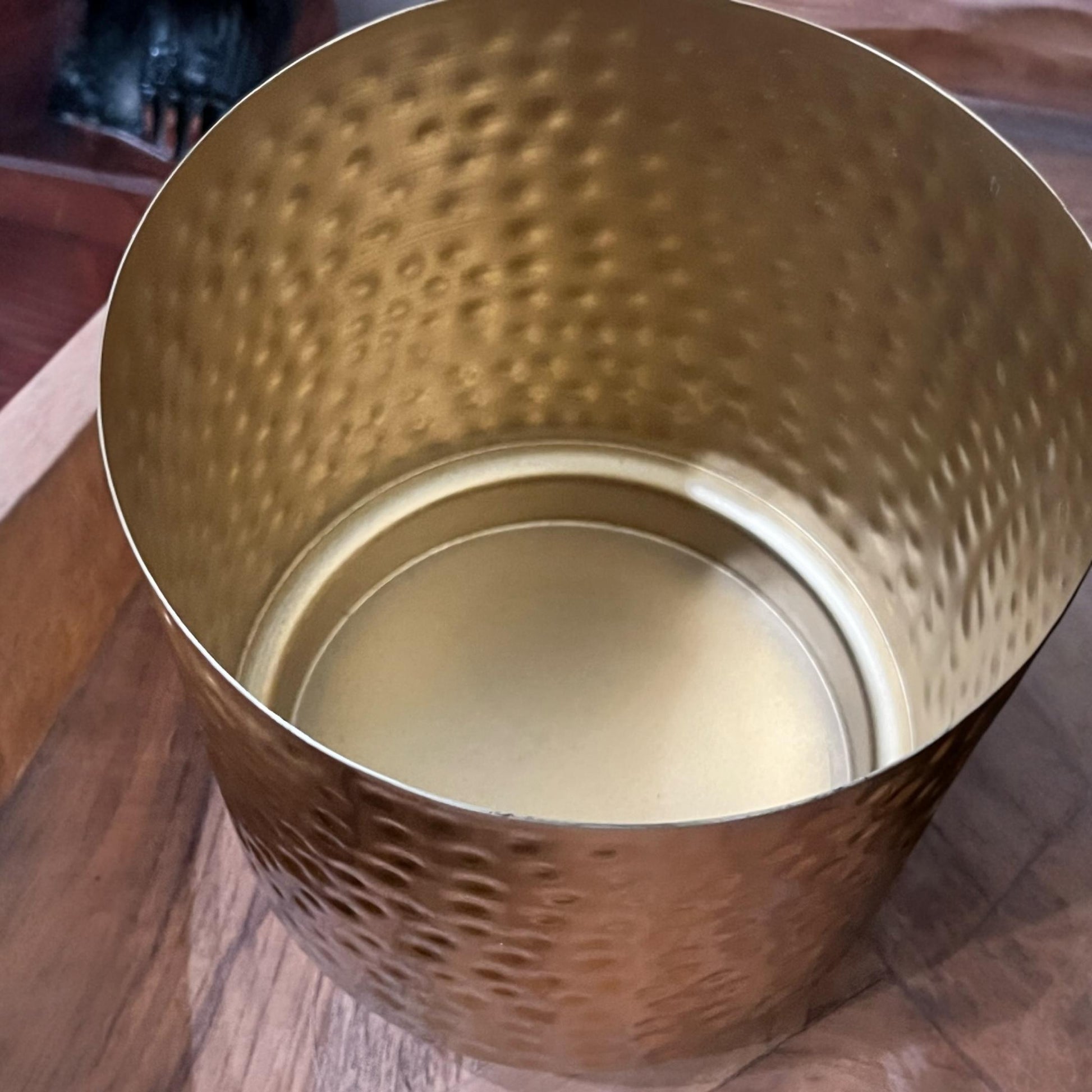 Close-up of the radiant gold finish and artisanal hammered texture on a premium iron planter.