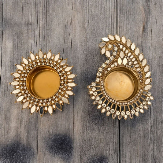 Diwali table décor with Sunflower & Mango Paisley mirror diyas, Pair of gold t-light with intricate designs on a wooden surface