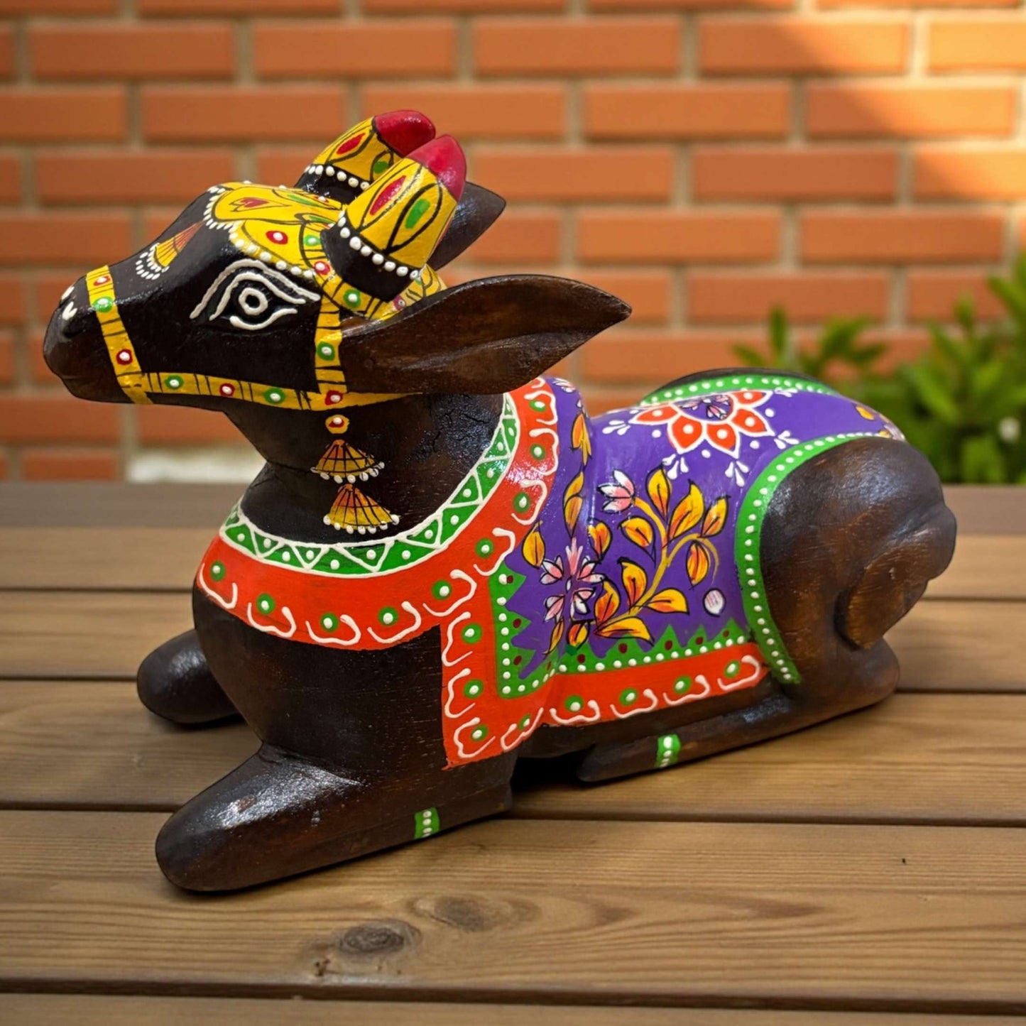 Decorative wooden figure of a cow with colorful patterns on a wooden surface.