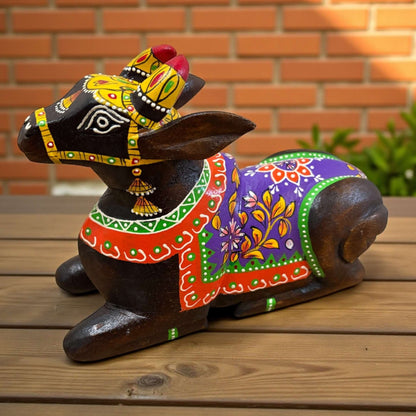 Decorative wooden figure of a cow with colorful patterns on a wooden surface.