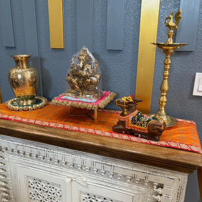 Decorative setup with gold figurines and vases on a wooden surface against a blue wall.